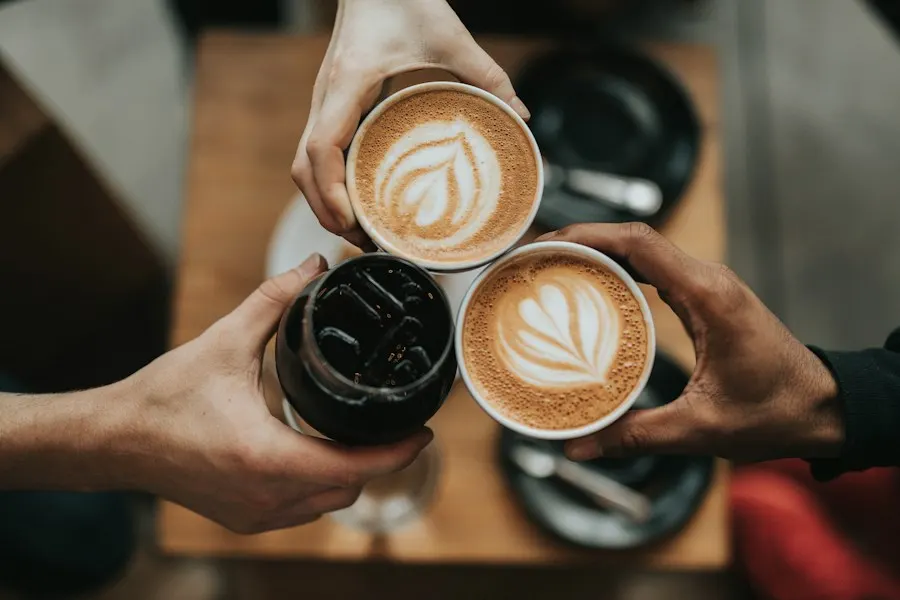 Friends raising cappuccinos over a café table
