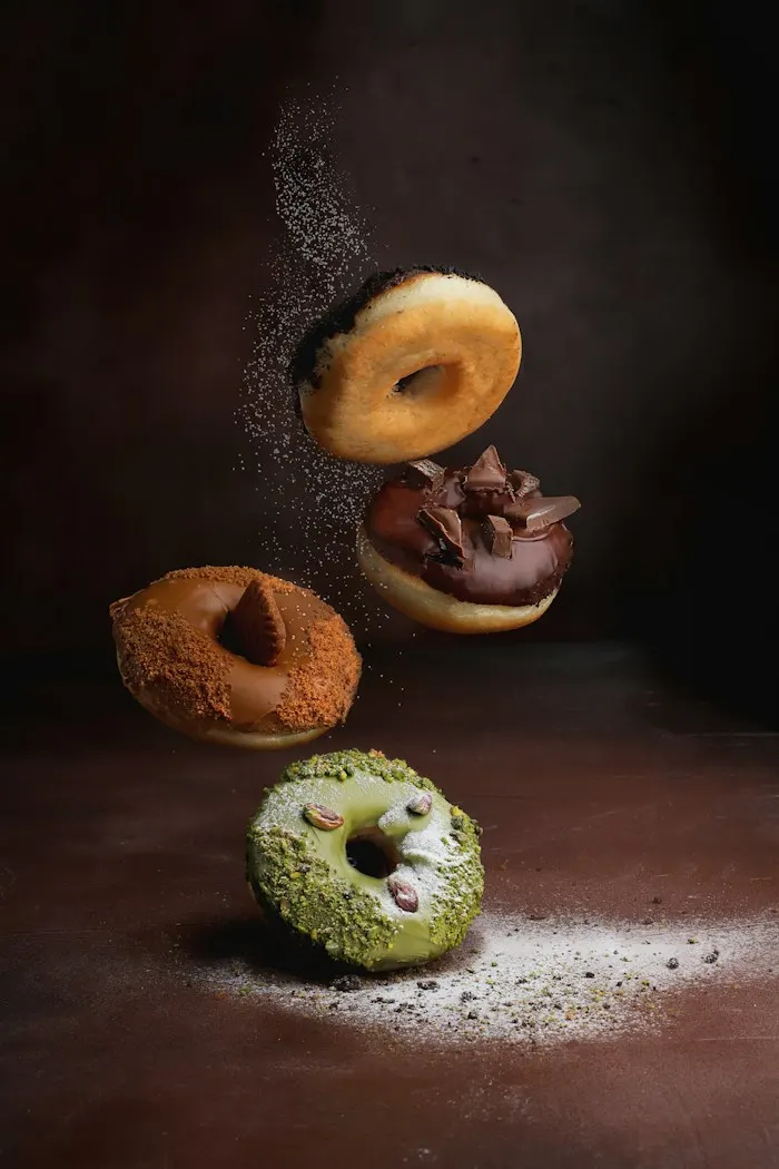 Donuts in mid-air, one topped with pistachio